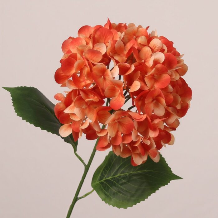 Orange faux hydrangea stem with layered petals and realistic leaves, suitable for wedding decor, event floral arrangement, and hotel styling