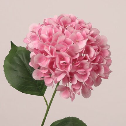 Light pink faux hydrangea stem with layered petals and lifelike leaves, suitable for wedding decor and event floral arrangements