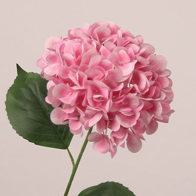 Light pink faux hydrangea stem with layered petals and lifelike leaves, suitable for wedding decor and event floral arrangements
