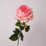Bright pink faux rose stem with layered petals and natural green leaves used for wedding decor and event floral styling