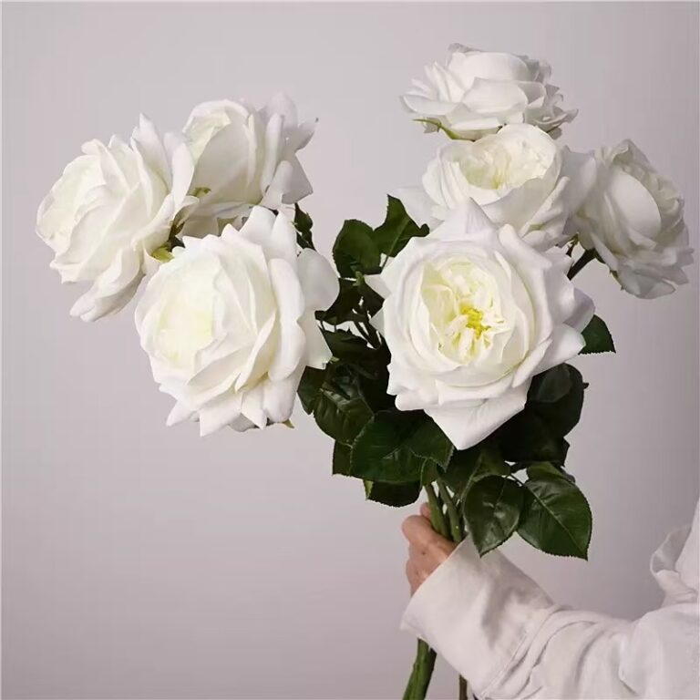 Cream peach and white faux rose stems with lush layered petals and green foliage for wedding and event floral arrangements