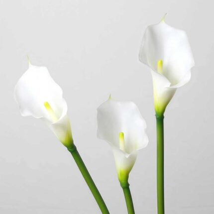 White faux calla lily stems arranged in a trio with elegant curved blooms for wedding decor and event floral arrangement