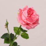 Bright pink faux rose stem with layered petals and natural green leaves used for wedding decor and event floral styling