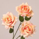 Peach faux rose spray with warm gradient petals and natural leaves for wedding and event floral decor