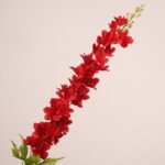 Red faux delphinium stem with bold layered petals and realistic foliage for wedding decor and event floral arrangements