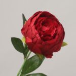 Close-up of a premium deep red artificial peony bloom with realistic silk petals and green leaves by NB8