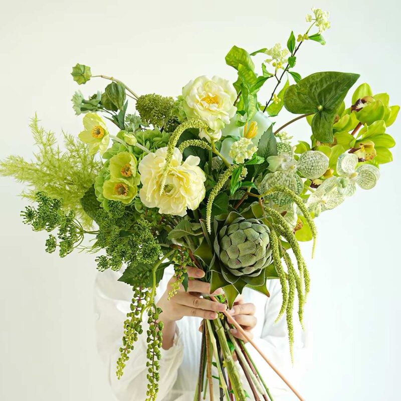 A lush green and yellow floral arrangement with artichoke and orchids