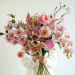 Pink floral arrangement with lilies, roses, orchids, and peonies