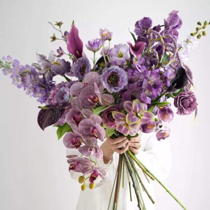 Purple orchid and calla lily floral arrangement with dark foliage