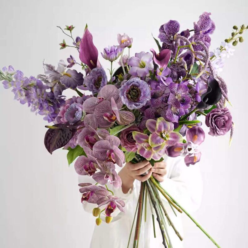 Purple orchid and calla lily floral arrangement with dark foliage
