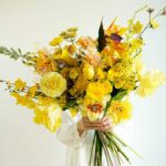 Bright yellow floral arrangement with roses, tulips, and lilies