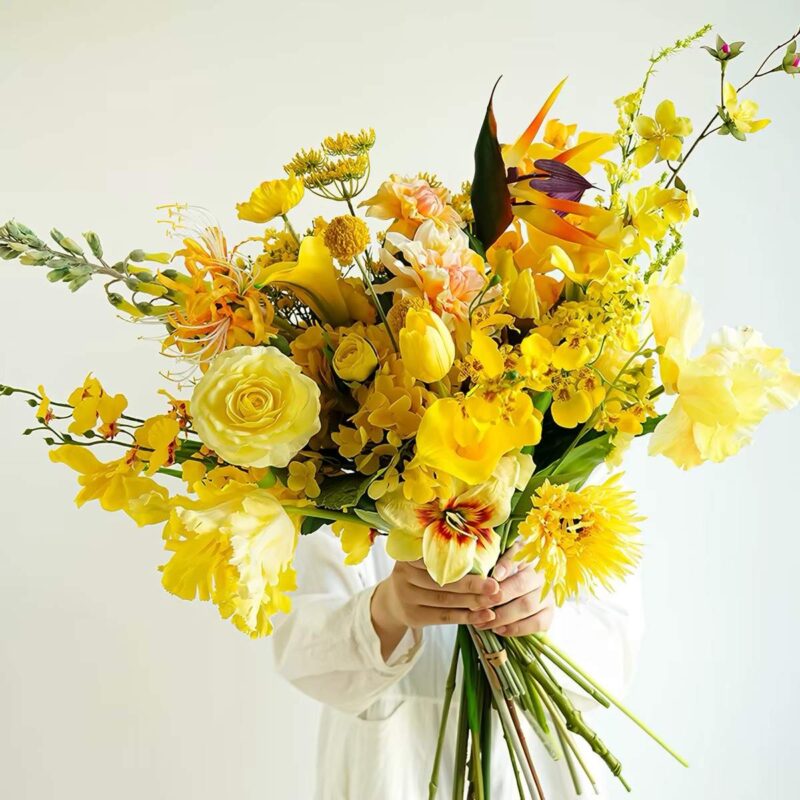 Bright yellow floral arrangement with roses, tulips, and lilies
