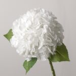 Large white faux hydrangea flower head with realistic, multi-layered silk petals and two textured green leaves on a single green stem.
