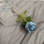 Artificial blue silk rose with green leaves, perfect for lasting decor or crafting projects.