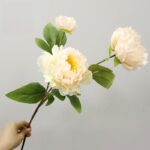 Three artificial silk peony flowers with green leaves bouquet for home decor.
