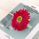 Artificial pink gerbera daisy flower prop displayed on a decor book