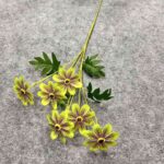 Artificial silk daisies with leaves displayed on gray background for crafting decor.
