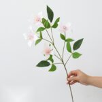 Artificial silk clematis flower stem with white blossoms and green leaves for home decor.