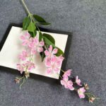 Silk pink jasmine floral garland decoration set against a modern plaque, perfect for wedding or home decor.