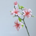 Artificial silk magnolia flowers on branches, featuring soft pink blooms and green leaves for home décor