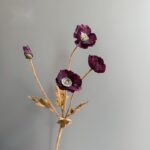 Artificial silk poppy arrangement featuring four deep purple flower heads on stems.