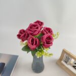 Bouquet of artificial pink silk roses with green filler flowers in a vase.