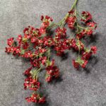 Artificial red silk flowers arrangement on a gray background, suitable for home decor.