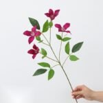 Artificial silk clematis flowers in deep pink hues, presented on green stems for home decor.