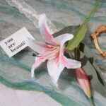 Beautiful silk lily bouquet styled with personalized message cards on marbled surface.