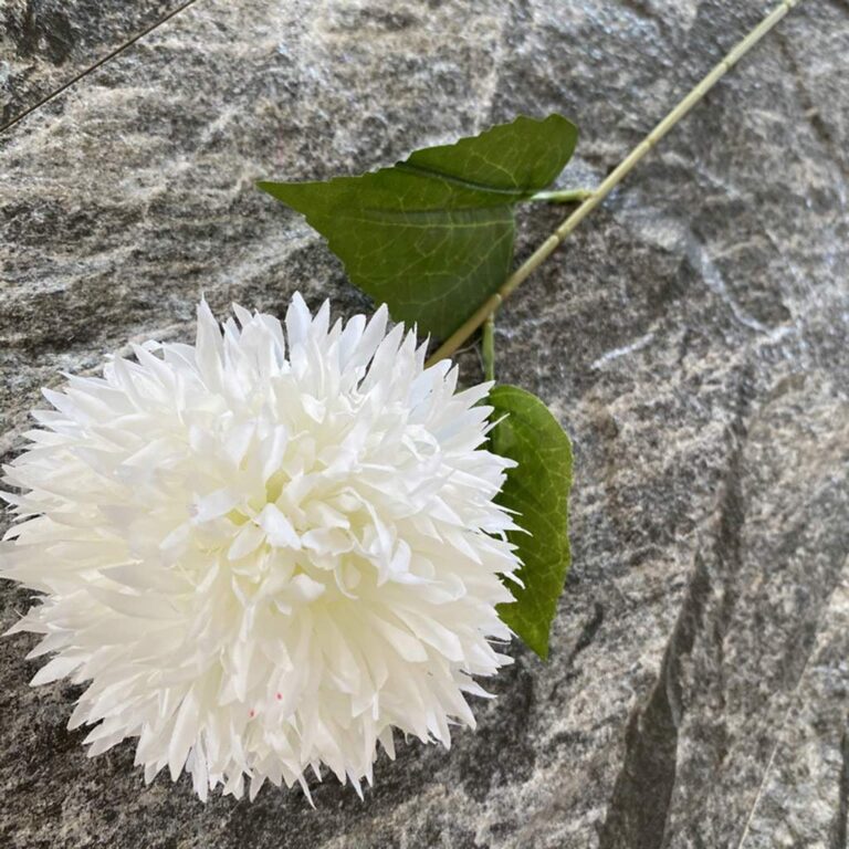 White silk pompon flower arrangement with leaves on gray stone, suitable for artificial wedding flowers or home decor.