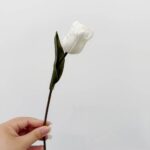 Hand holding a realistic white artificial tulip stem, perfect for home or wedding decor accents.