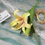 Yellow silk lily artificial flower arrangement centerpiece on blue marble background