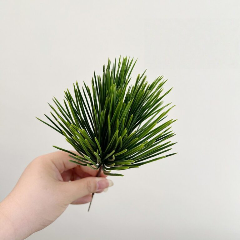 Hand holding realistic faux green palm leaves perfect for wedding decor or home use.