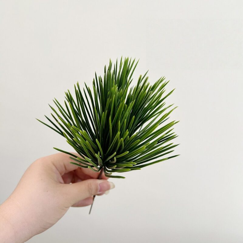 Hand holding realistic faux green palm leaves perfect for wedding decor or home use.