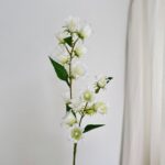 White silk bluebell floral branch decoration standing against a plain white background