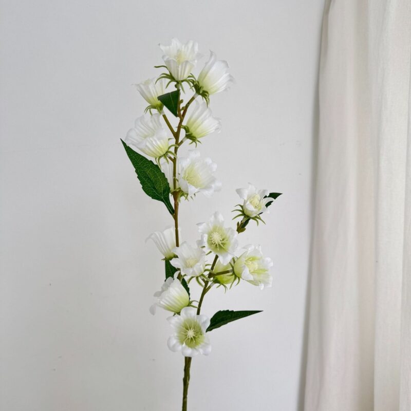 White silk bluebell floral branch decoration standing against a plain white background