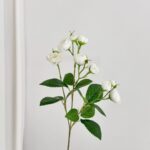 White artificial silk roses bouquet with green foliage for home decor.