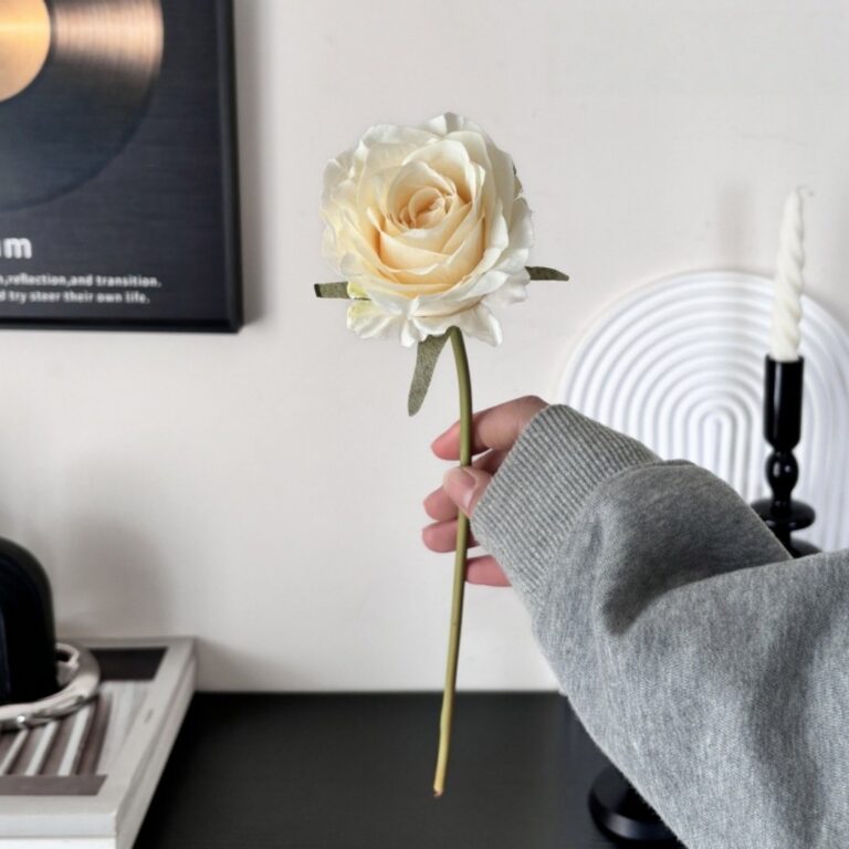 Elegant cream faux silk rose held in a hand, perfect artificial floral decor and everlasting bouquet for home use.