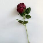 Artificial burgundy silk rose on stem with vibrant green leaves for home décor and craft projects