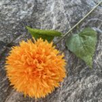 Realistic orange silk pompon ball flower with green leaves for artificial wedding flowers or home decor.
