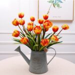 Artificial silk tulip arrangement with bright orange blooms in an antique galvanized pitcher.