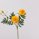 Three heads of artificial silk marigolds with green foliage perfect for floral arrangements.