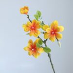 Fake yellow magnolia flowers silk arrangement on dark branches, perfect faux floral home decor accent.