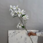 Artificial white lilies branch, featuring 12 realistic fabric flower heads for home decor.