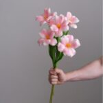 Hand holding a delicate bouquet of realistic pink artificial tulips (Real touch Tulip YWKX2005).