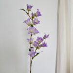 Artificial silk bluebells in various shades of purple and lavender on a branch