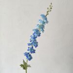 Artificial blue silk delphinium flowers on a spray stem for home decor arrangements.