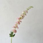 Artificial silk delphinium floral spray bouquet against a light gray background for decor.