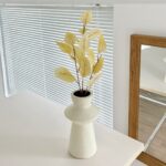 Decorative faux silk leaves bouquet in neutral pottery vase for modern home decor.