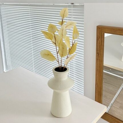 Decorative faux silk leaves bouquet in neutral pottery vase for modern home decor.